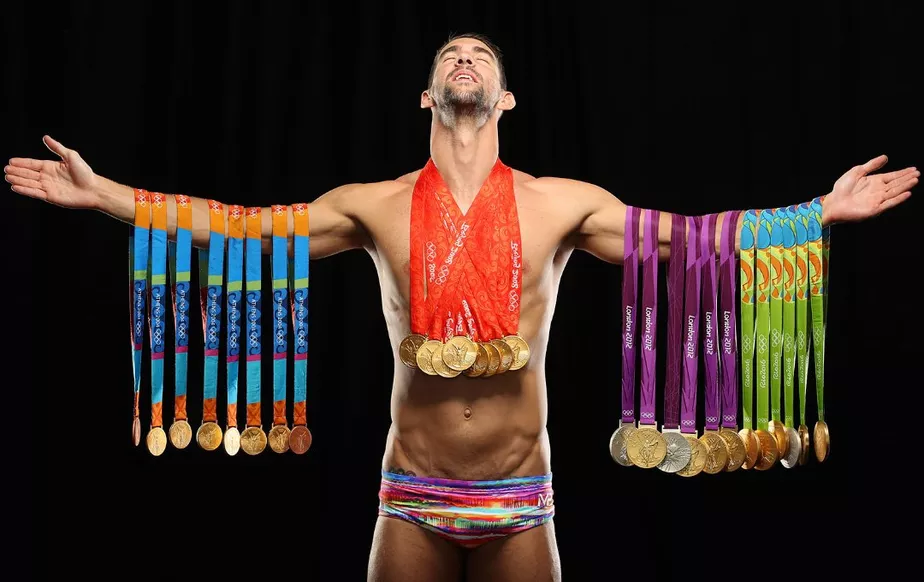 Imagem de Michael Phelps segurando todas suas medalhas ganhas em Olimpíadas.